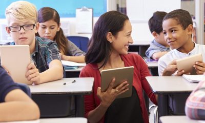 Teacher among kids with computers in elementary school class