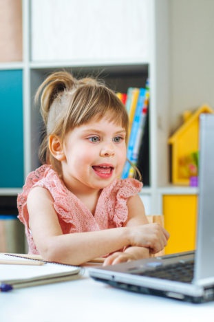 A girl interacts with voice tech via a laptop. 